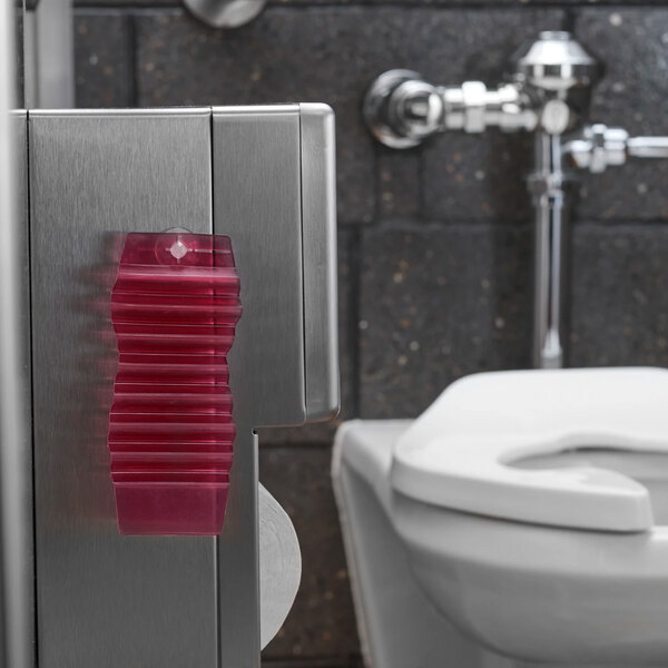 A red passive air freshener hang tag attached to a metal surface in a restroom.