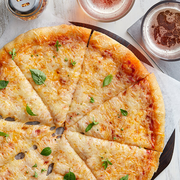 A cheese pizza with Daiya vegan Italian blend cheese and basil leaves on a plate.