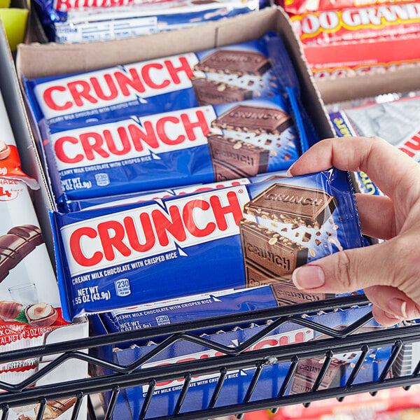 A hand holding a package of CRUNCH chocolate bars.