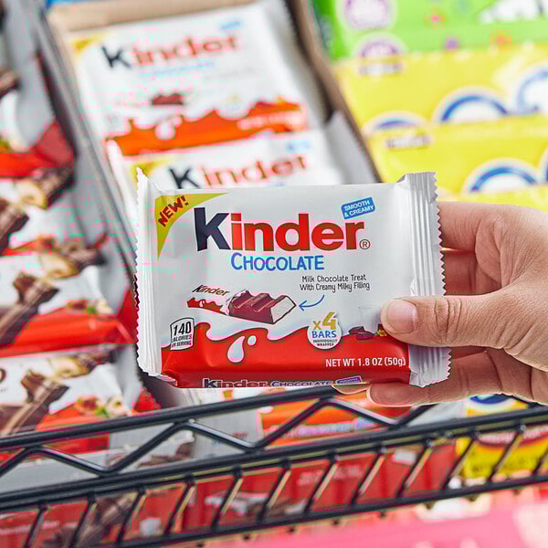 A hand holding a package of KINDER® Chocolate bars.