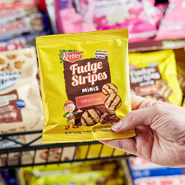 A person holding a package of KEEBLER Fudge Stripes Minis.