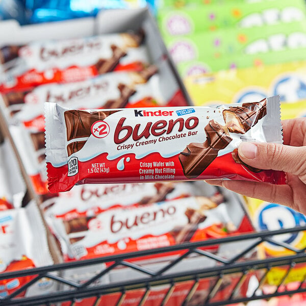 A hand holding a KINDER Bueno hazelnut milk chocolate bar.