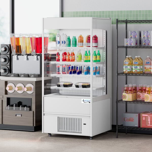 An Avantco white vertical air curtain merchandiser with a variety of drinks and beverages on display.