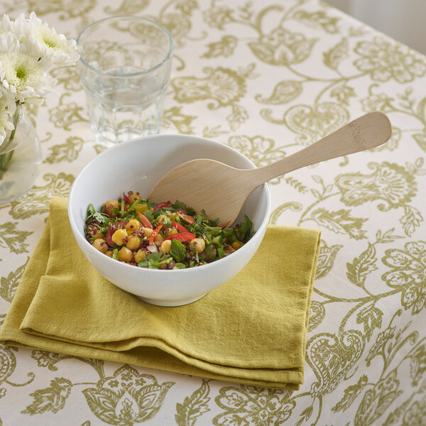 A bowl of salad with a Bambu Veneerware bamboo serving spoon.