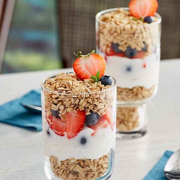 Two glasses of yogurt topped with strawberries, blueberries, and Bob's Red Mill Gluten-Free Honey Oat Granola.