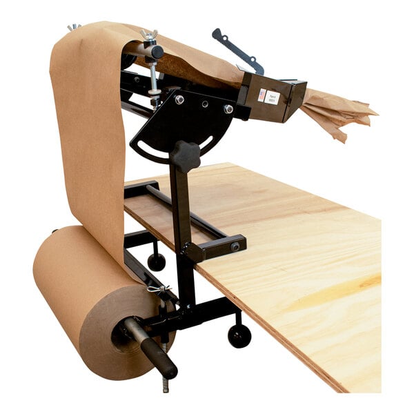 A wood table with a white steel paper roll holder with a roll of brown paper.