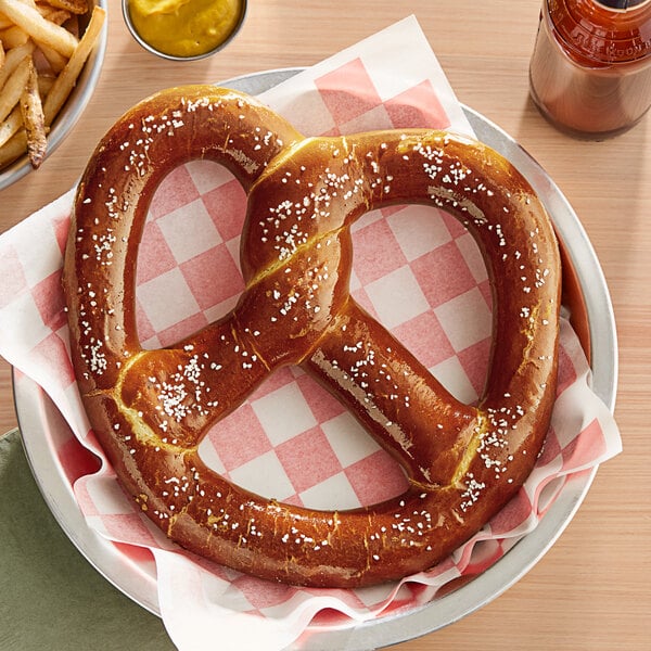 A large Ditsch soft pretzel on a plate with a salt packet.