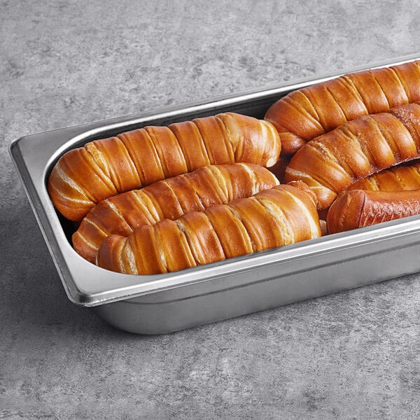 A metal tray of Ditsch German frozen soft pretzel sticks with a salt packet on a table.