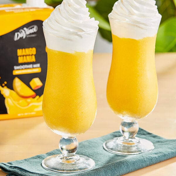 Two glasses of DaVinci Gourmet Mango Mania smoothie with whipped cream on top.