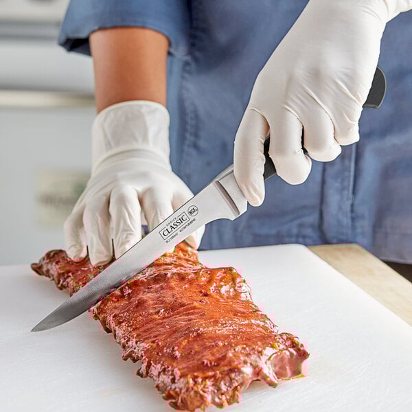 A person using a Choice Classic narrow stiff boning knife with white gloves to cut meat on a counter.