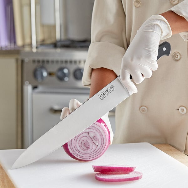 A person wearing gloves uses a Choice Classic Chef Knife to slice a red onion on a cutting board.