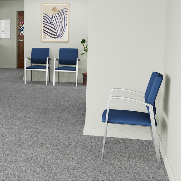 A blue vinyl guest arm chair with silver powder-coated steel legs placed in a waiting room.