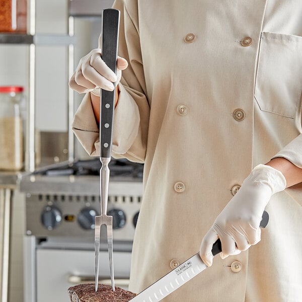 A person holding a Choice Classic forged carving fork with a POM handle.