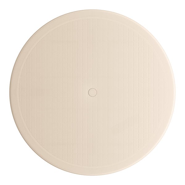 A sandstone Grosfillex pedestal table with a circular design in the middle.