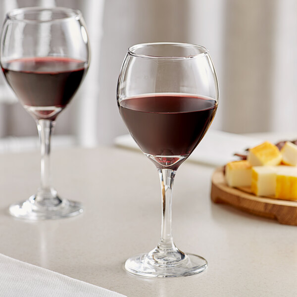 Two Acopa Bouquet wine glasses filled with red wine on a table.