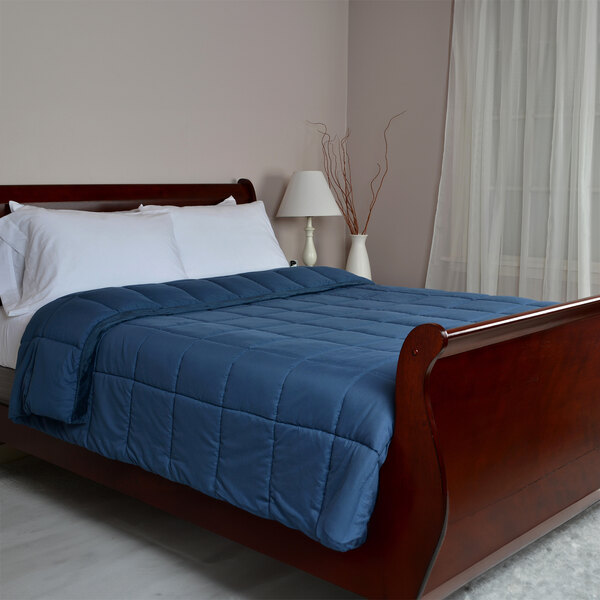 A bed with a Berkshire Hospitality Marine Polyester Blanket on it with white pillows.