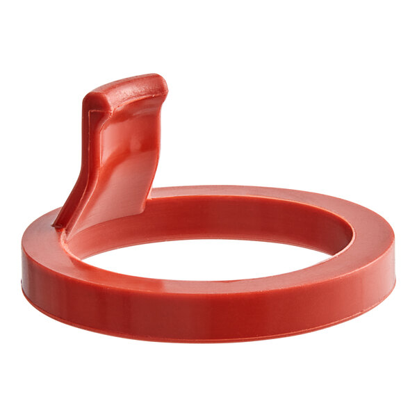 A red plastic Whip-It flat gasket with a handle.