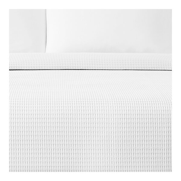 A white Berkshire Hospitality pucker jacquard top sheet on a bed with a white pillow.