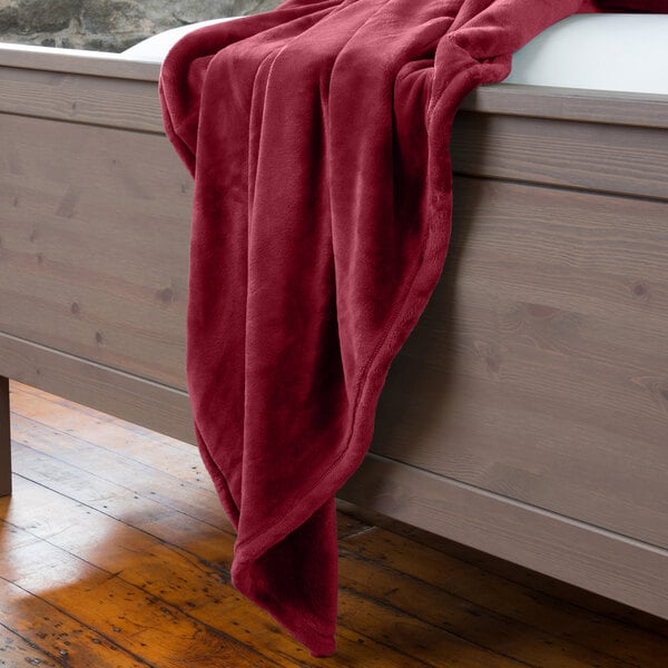 A garnet Berkshire Hospitality VelvetLoft throw blanket on a bed.