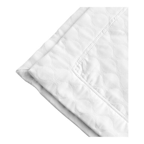 A close-up of a white quilted Berkshire Hospitality Ogee Matelasse coverlet with a white border.