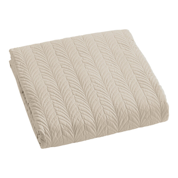 A beige Berkshire Hospitality quilt coverlet with a botanical leaf pattern.