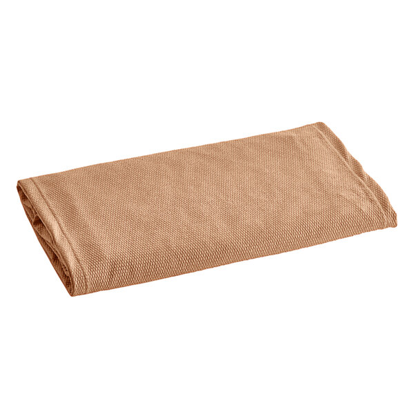 A tan knit box spring cover folded up on a white background.
