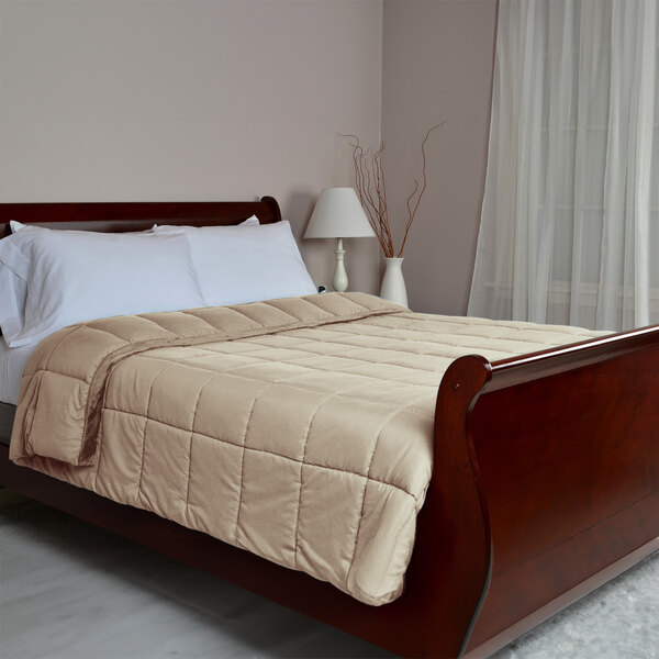 A bed with a mocha Berkshire Hospitality blanket on a wooden sleigh bed.