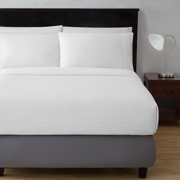 A bed with a Berkshire Hospitality white king size top sheet and pillows.