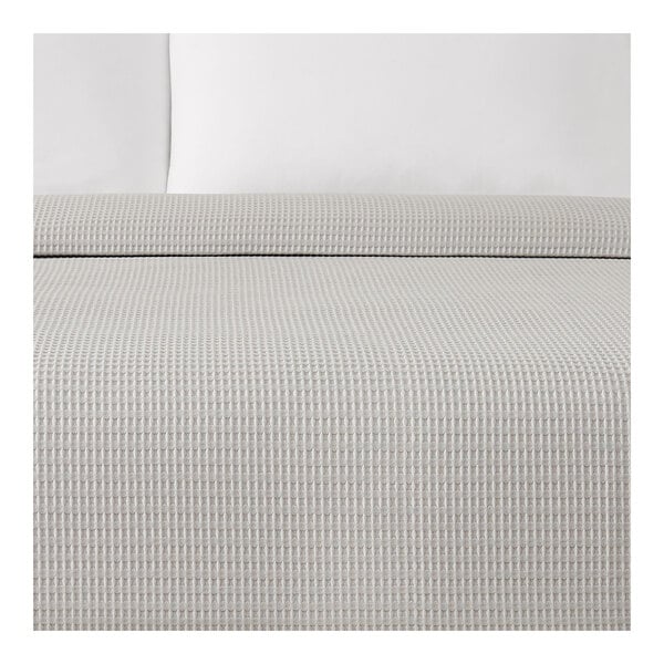A Berkshire Hospitality gray jacquard top sheet on a bed with white pillows and comforter.