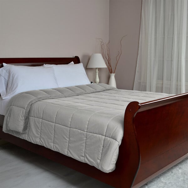 A king size bed with a Berkshire Hospitality smoke down alternative blanket and white bedding.