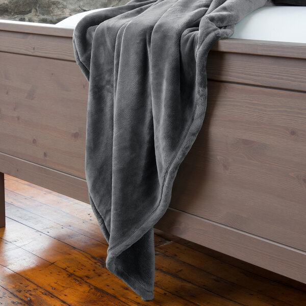 A charcoal Berkshire Hospitality throw blanket on a bed.