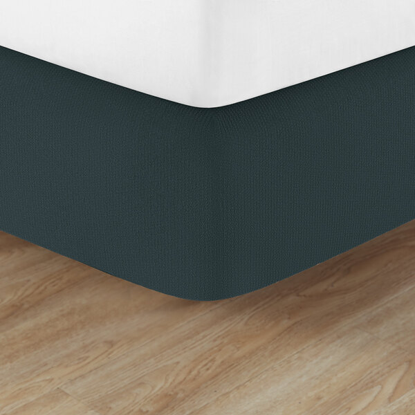 A close up of a bed with a Berkshire Hospitality Malachite Helix Box Spring Cover on a mattress.