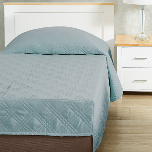A Berkshire Hospitality CozyCare blue fitted coverlet on a bed with a pillow.
