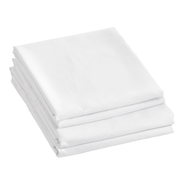 A close-up of a stack of Berkshire Hospitality SuiteDream queen size white microfiber sheets.