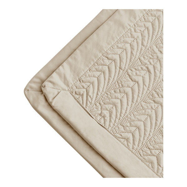 A beige quilted Berkshire Hospitality coverlet with a botanical leaf pattern.