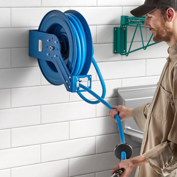 A man holding a Regency Blue powder-coated steel hose reel with a blue hose.