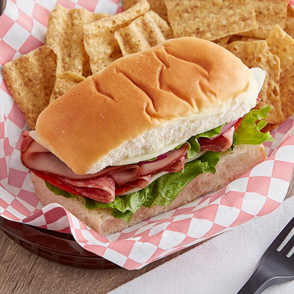 A sandwich with King's Hawaiian Mini Sub Rolls and chips on a plate.