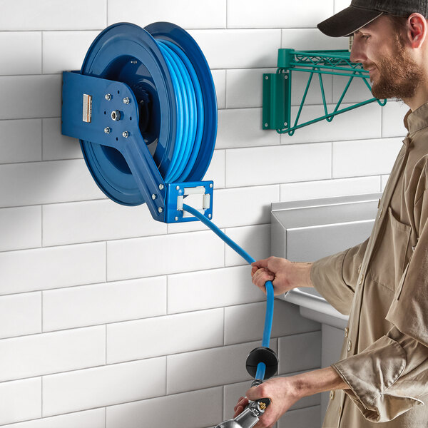 A man holding a Regency blue powder-coated steel hose reel.