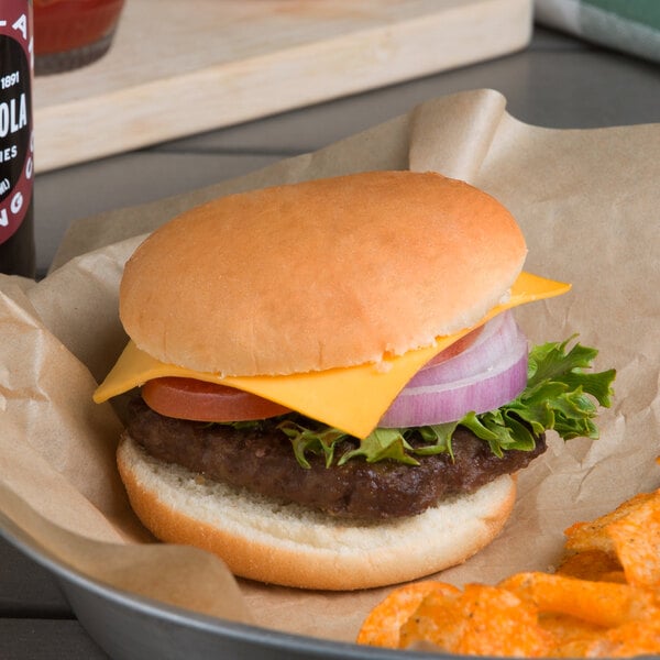 A cheeseburger with lettuce and onion on a Harvest Pride hamburger bun on a table.