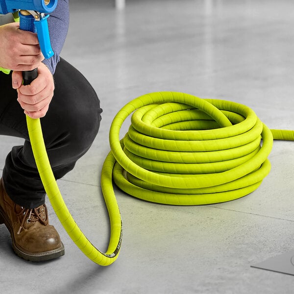 A person holding a coiled green Regency washdown hose.