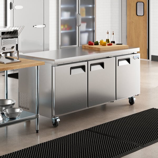 An Avantco stainless steel undercounter refrigerator on a large stainless steel kitchen counter.