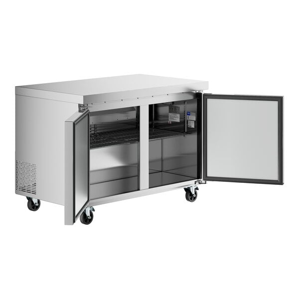 A stainless steel undercounter refrigerator with two open doors and interior shelving, mounted on caster wheels.