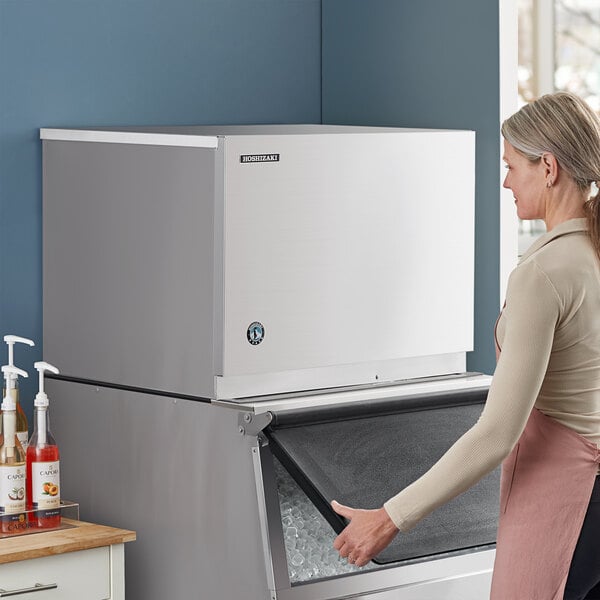 A woman opening the Hoshizaki KMD-505MWJ water cooled ice machine.