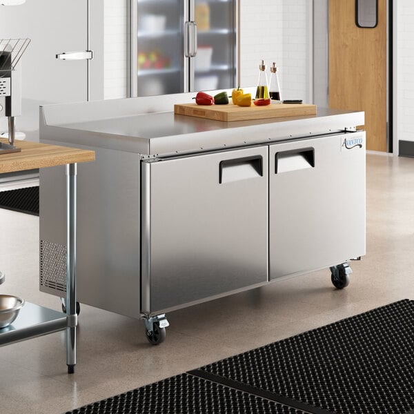 An Avantco stainless steel worktop freezer on a counter in a large professional kitchen.