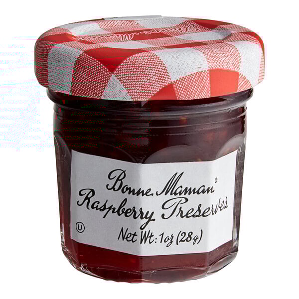 A Bonne Maman mini jar of raspberry preserves with a white label and a red lid.