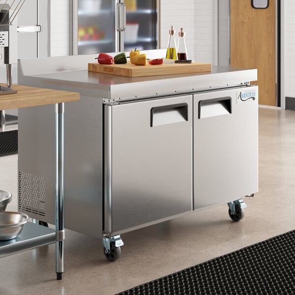 An Avantco stainless steel worktop freezer on a large counter with a cutting board on top.