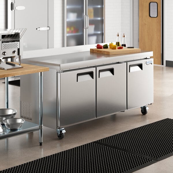 An Avantco stainless steel worktop refrigerator on a large counter top in a professional kitchen.