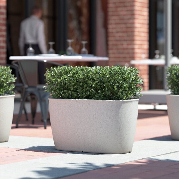 Three Lancaster Table & Seating Marie gray planters on an outdoor patio table.