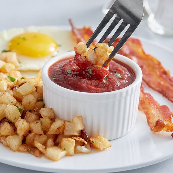 A fork with bacon and hash browns dipped in Sir Kensington's Classic Ketchup.