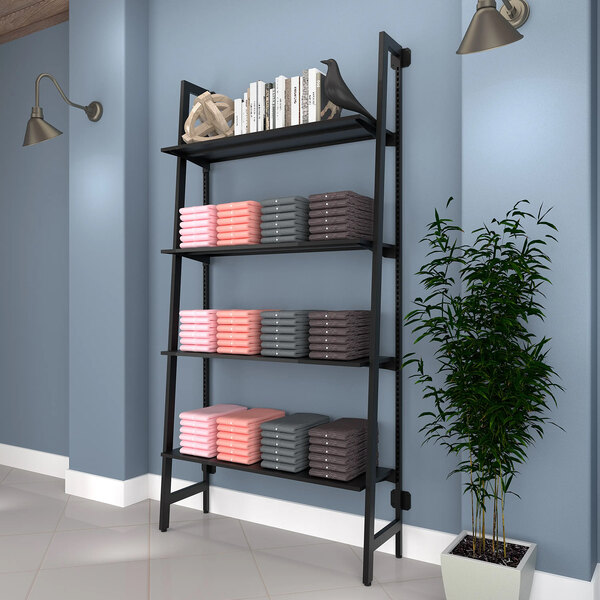 A black wall-mounted shelf with books and a plant in a pot.